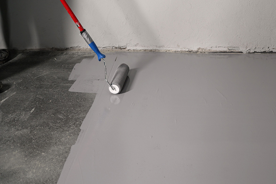 Applying epoxy floor coating over existing concrete surface to restore and protect garage floor